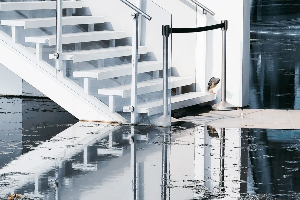 Standing water covering a concrete floor beside a white staircase